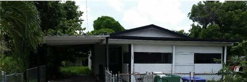 Exterior of a Liberty City single-family house before renovation showing worn paint and untidy landscaping