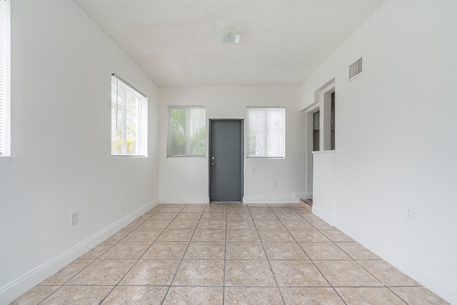 Interior de una unidad de renta lista para arrendar con piso tipo tablón imitación madera y paredes blancas nuevas en un edificio de apartamentos renovado en West Miami